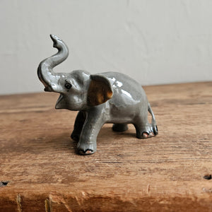 Miniature grey ceramic elephant trunk raised
