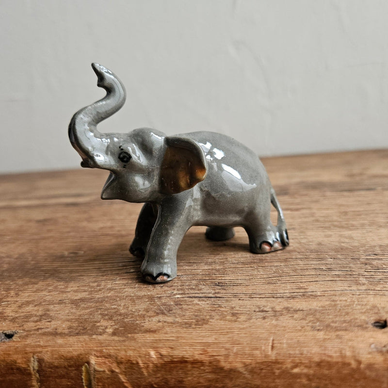 Miniature grey ceramic elephant trunk raised